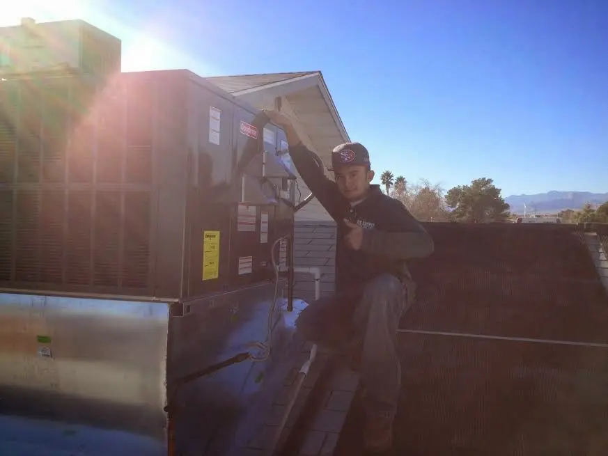 HVAC technician performing AC Tune-Up on a rooftop unit in Salida